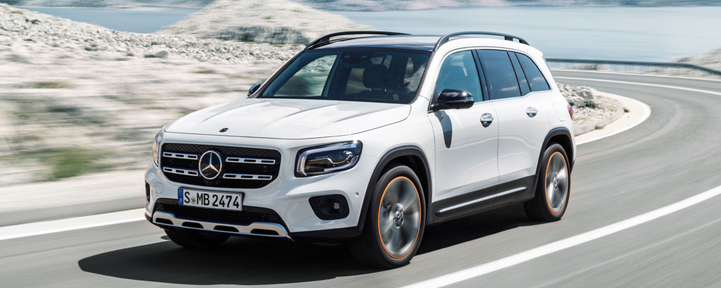 Mercedes-Benz GLB blanco circulando por carretera de montaña con vistas al mar