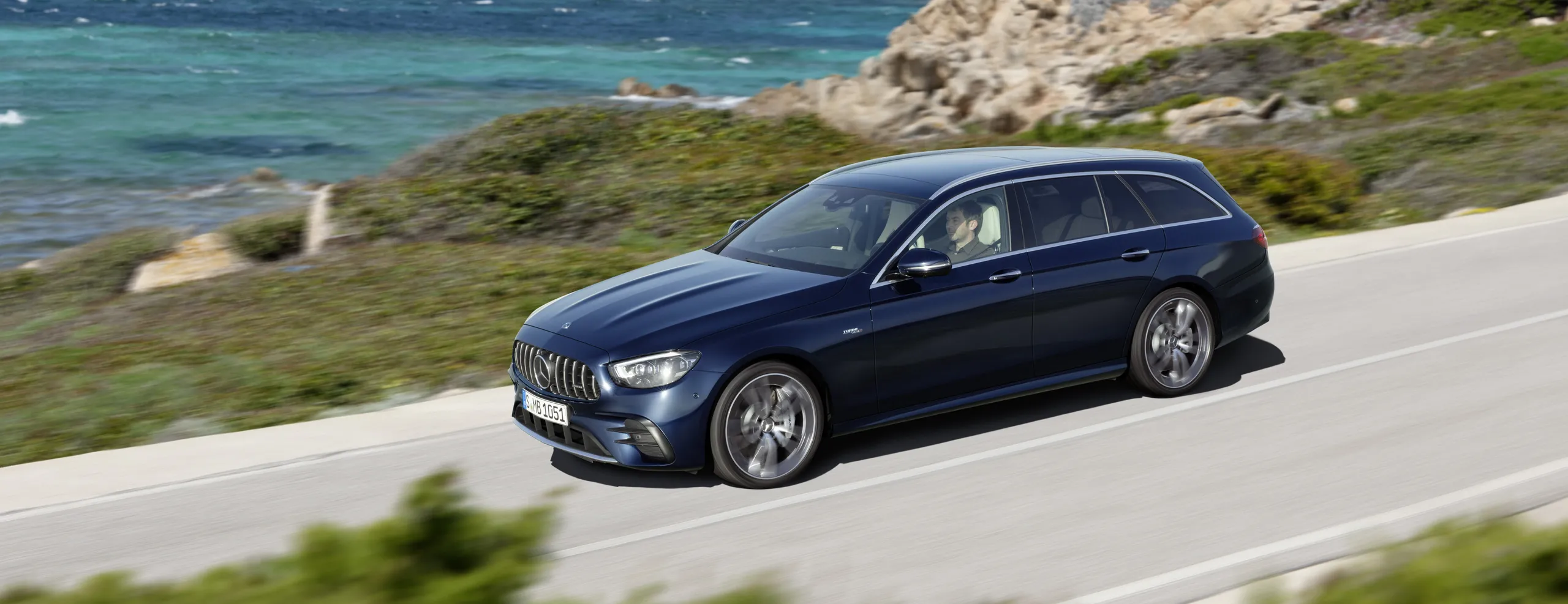Mercedes-AMG E63 Estate azul oscuro circulando por carretera costera
