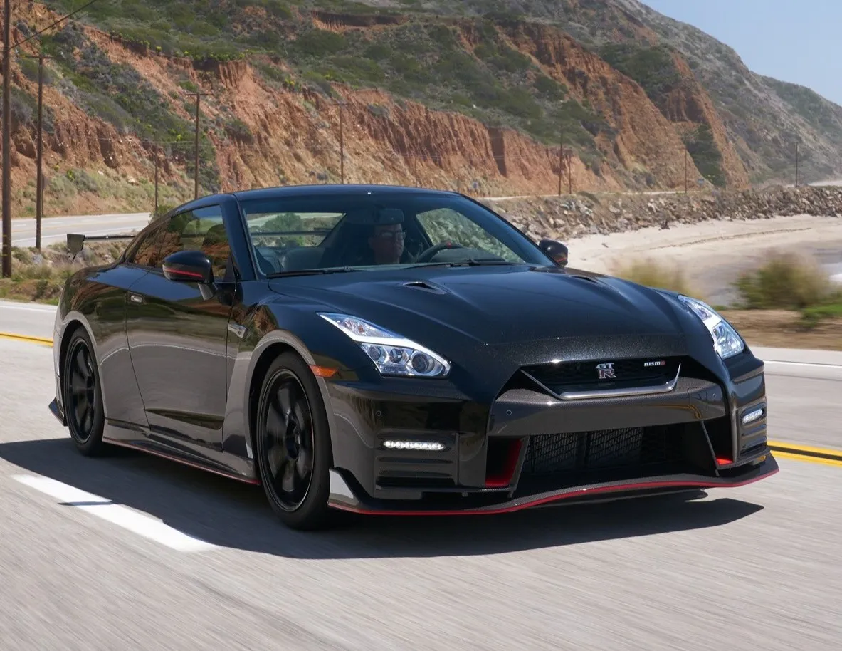 Nissan GT-R R35 negro circulando por carretera costera con acantilados