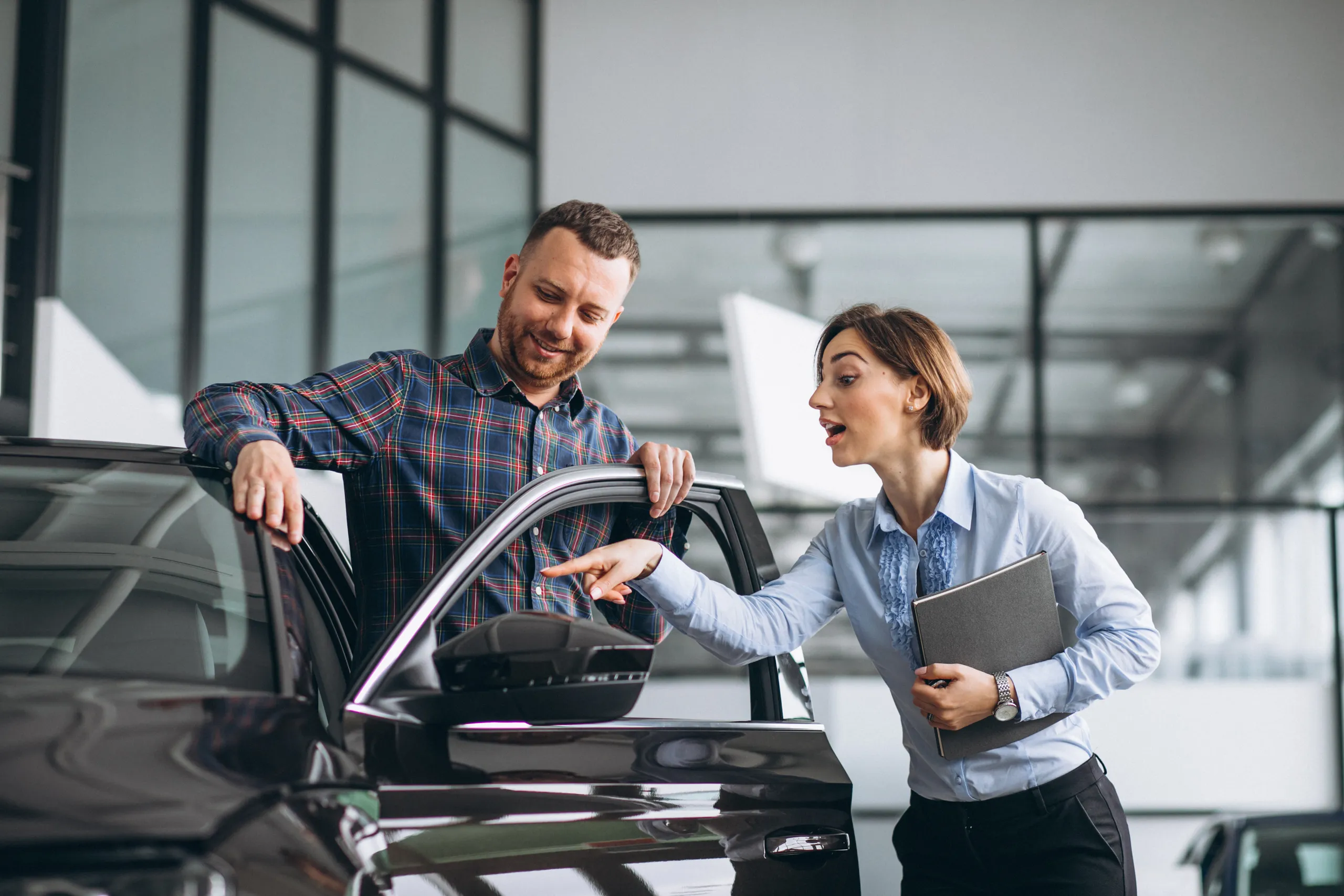 Vendedora con tableta asesorando cliente sobre financiación de coche nuevo