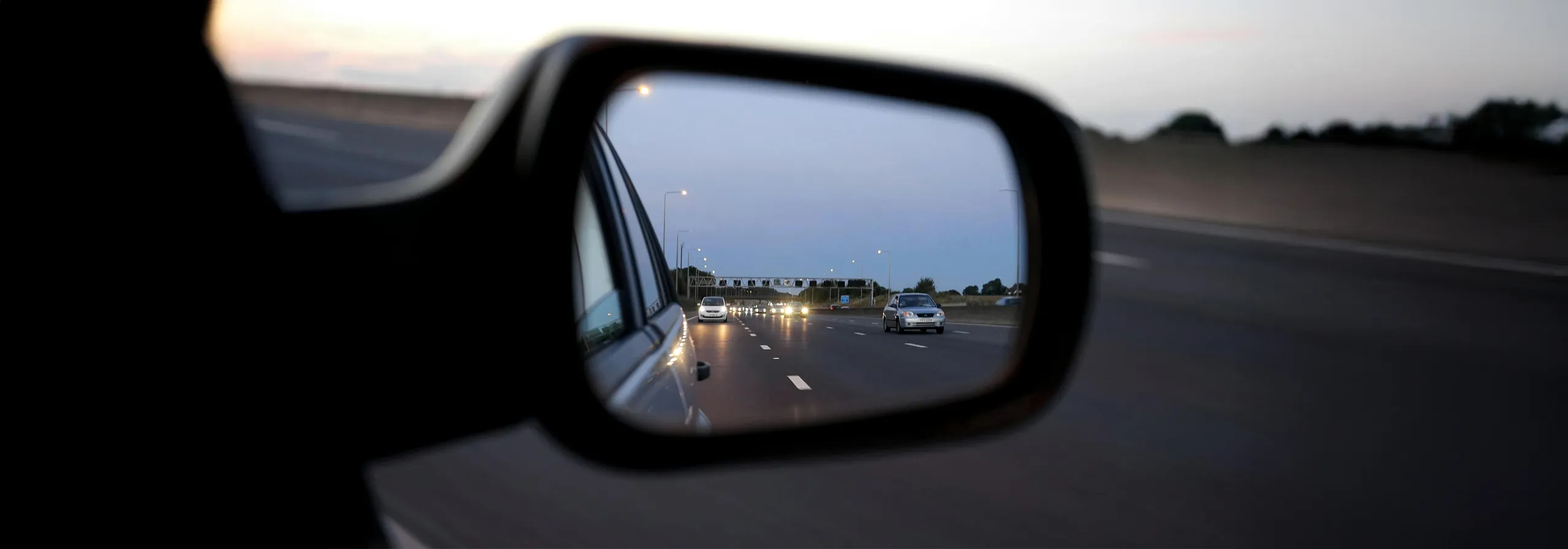 Vista trasera de vehículos en autopista durante atardecer con retención de tráfico