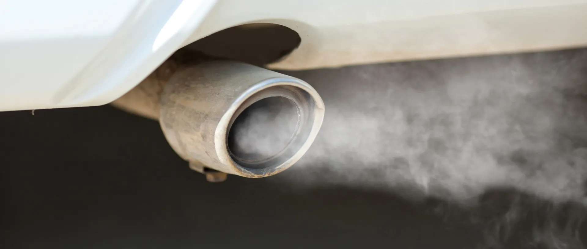 Tubo de escape de un coche expulsando humo blanco denso