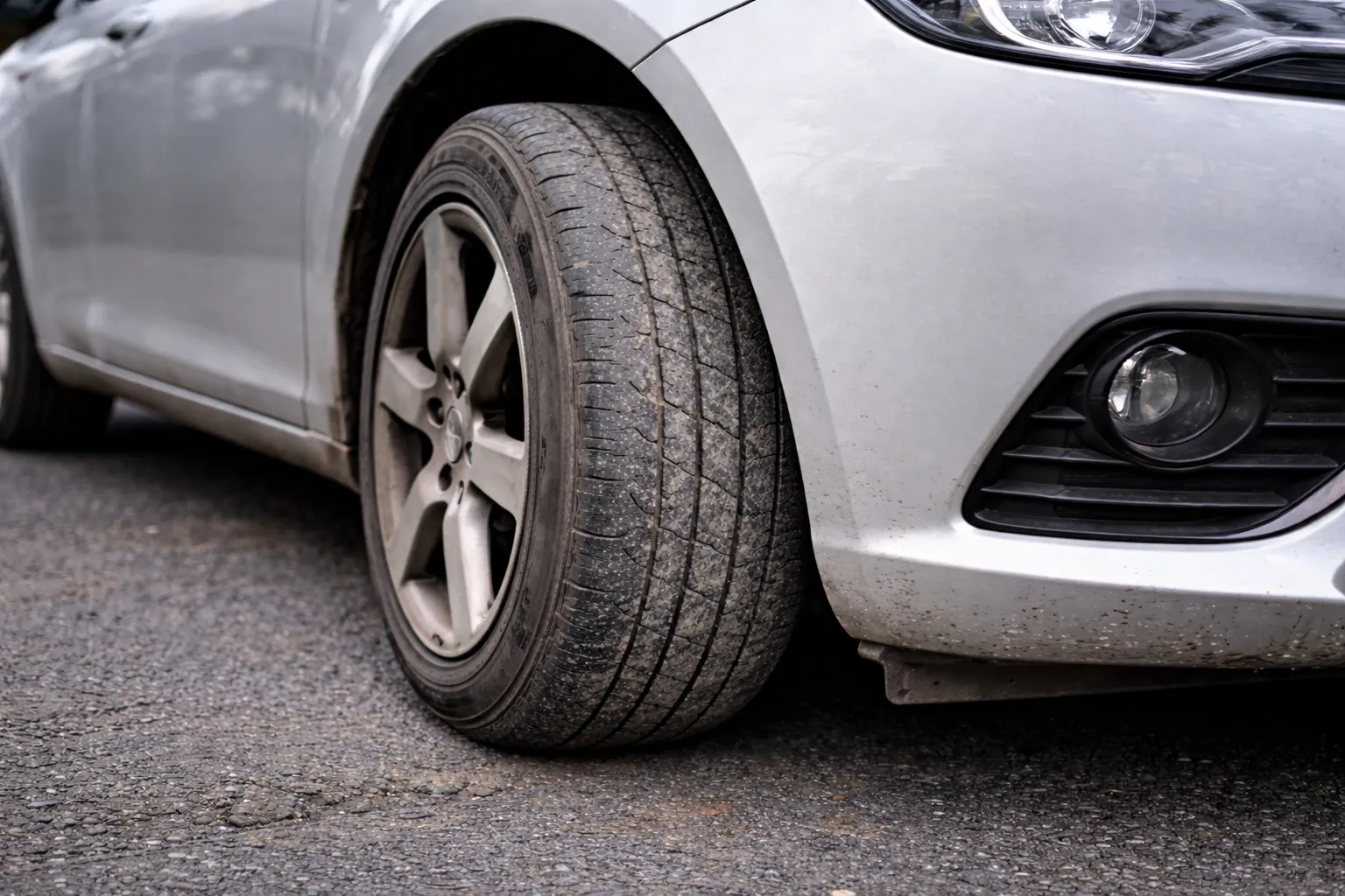 Neumático desgastado y agrietado en coche blanco que causa vibraciones