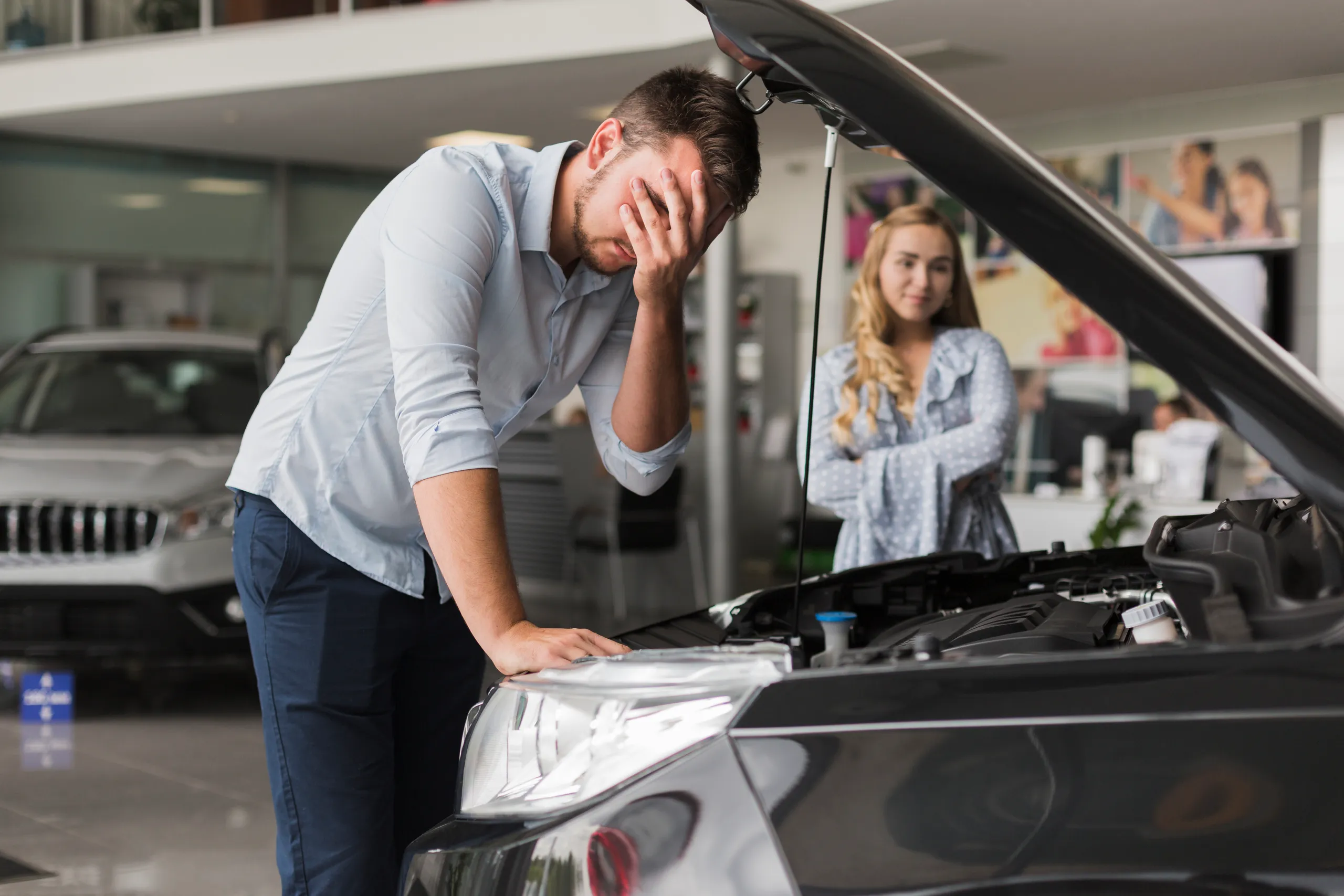 Cliente inspeccionando el motor de un coche usado en concesionario
