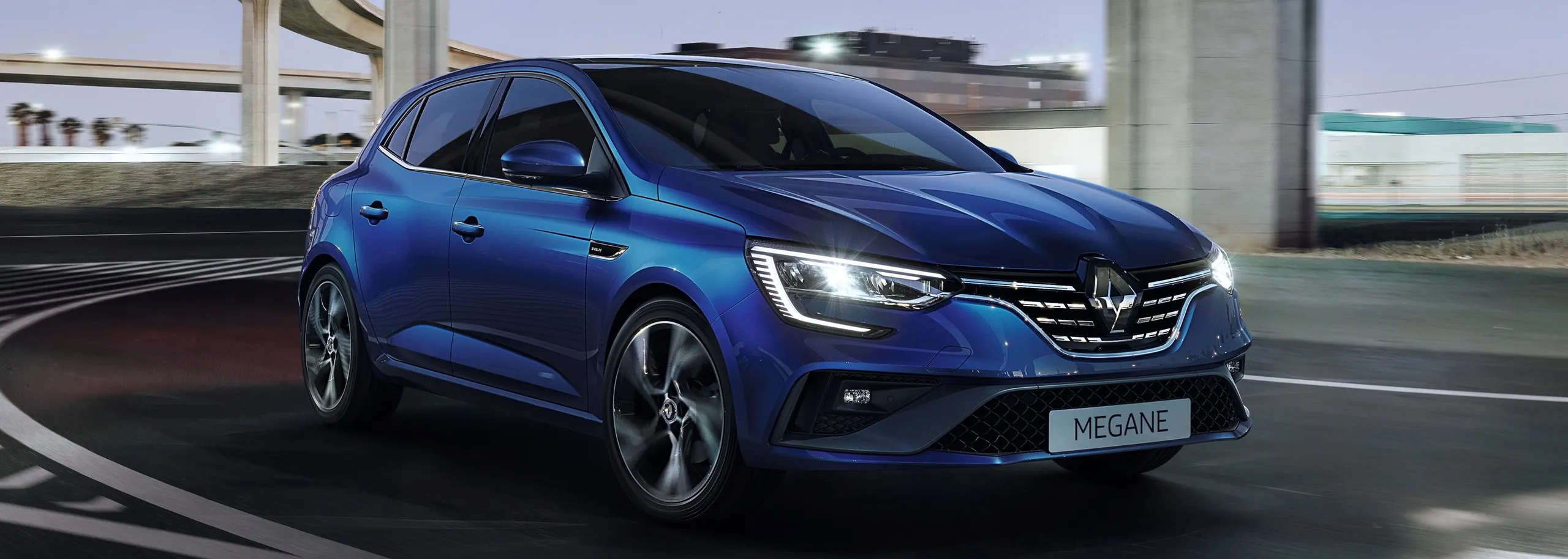 Renault Megane azul híbrido circulando por autopista, ideal para viajeros frecuentes