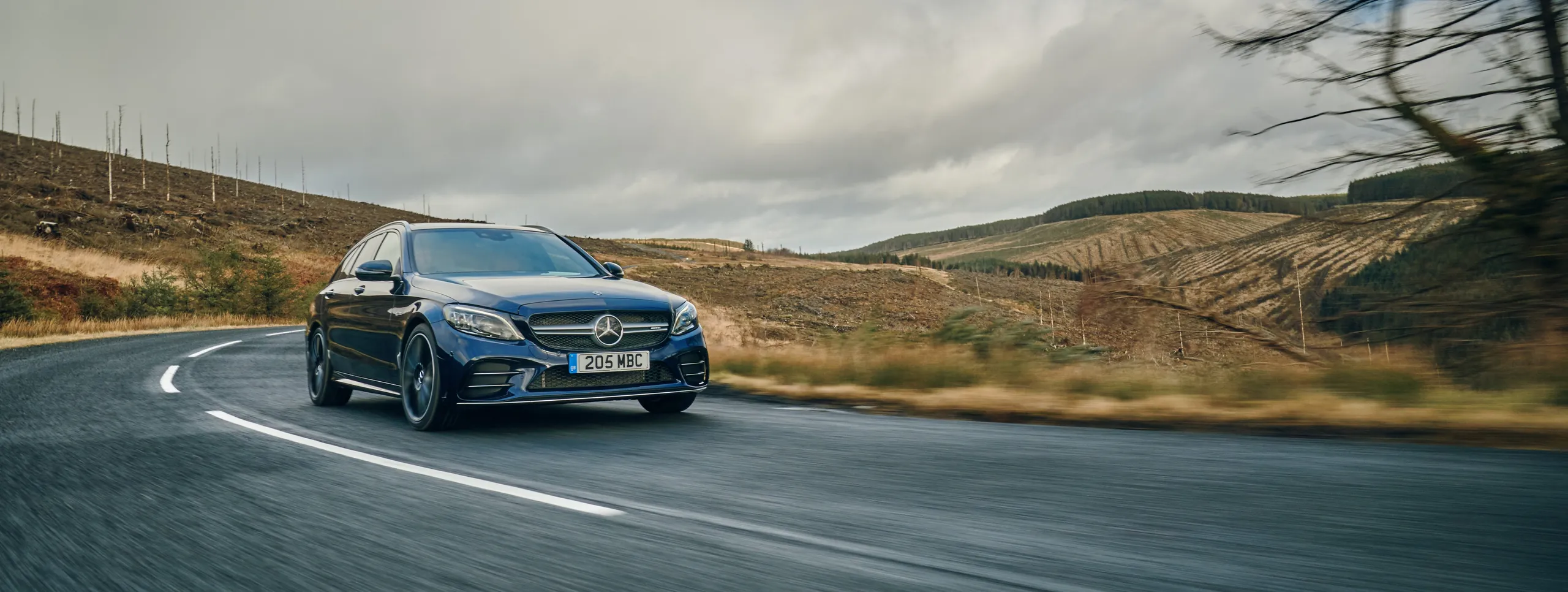 Mercedes-Benz azul circulando por carretera con paisaje montañoso