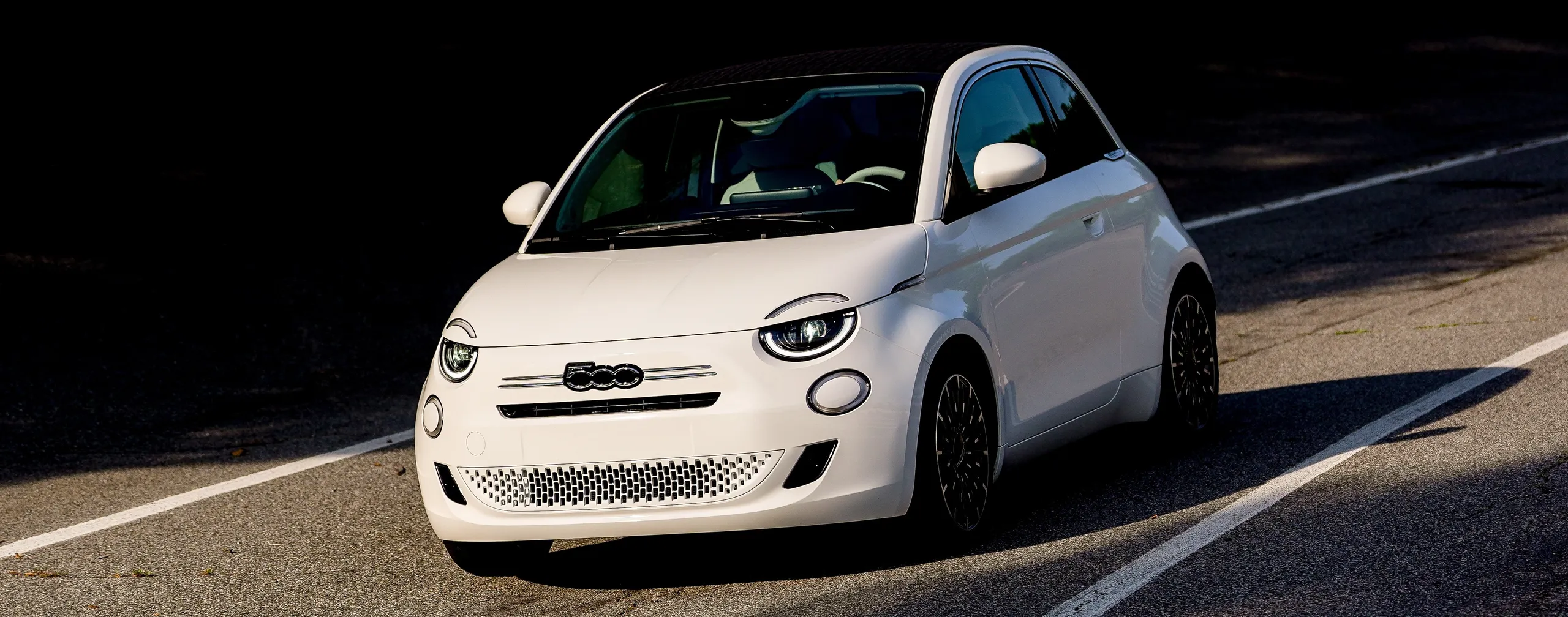 Fiat 500 blanco, segmento B, circulando por carretera con luz natural