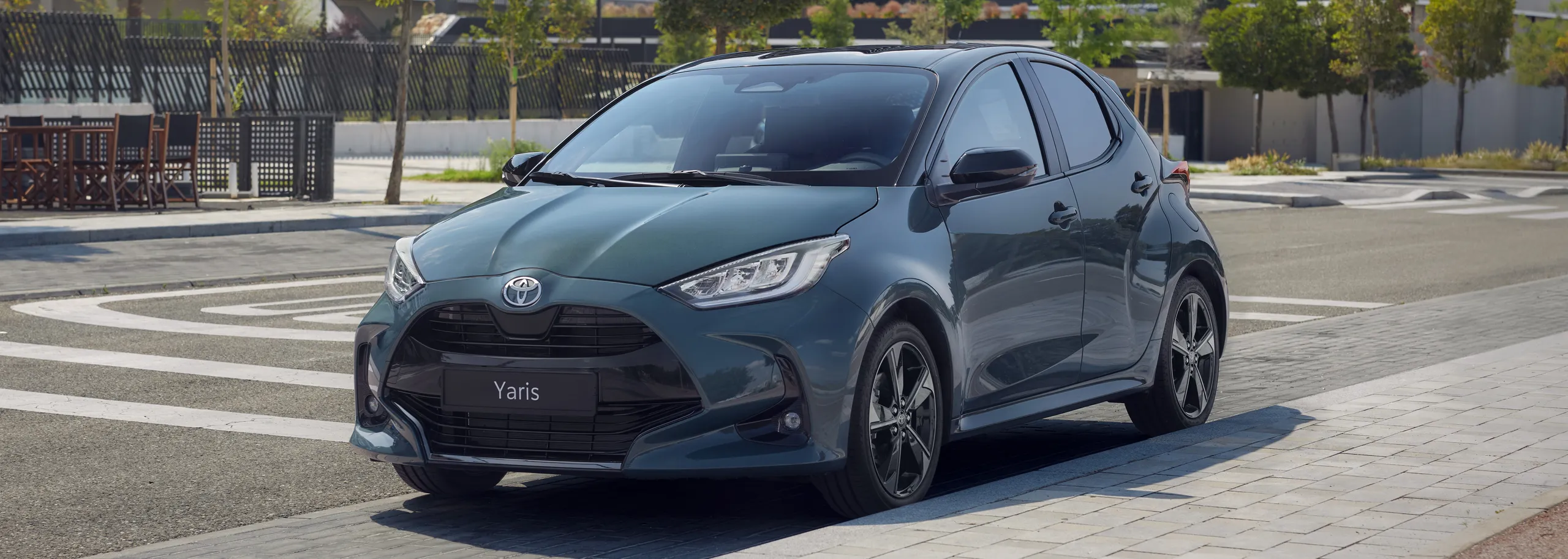 Toyota Yaris compacto azul aparcado en zona urbana con espacios verdes