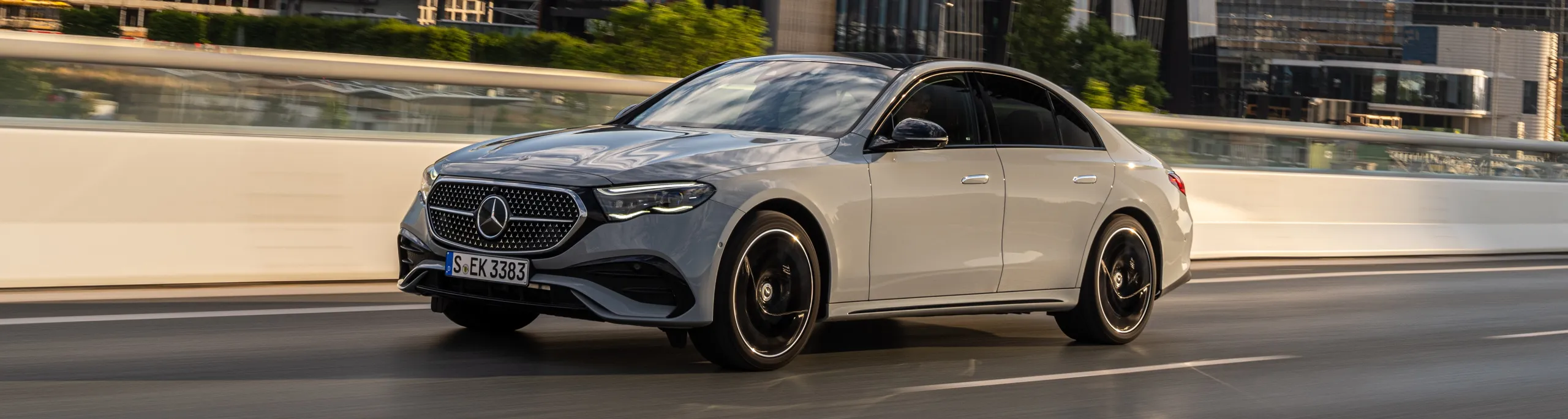 Mercedes sedán plata circulando por ciudad con postura elevada y diseño elegante