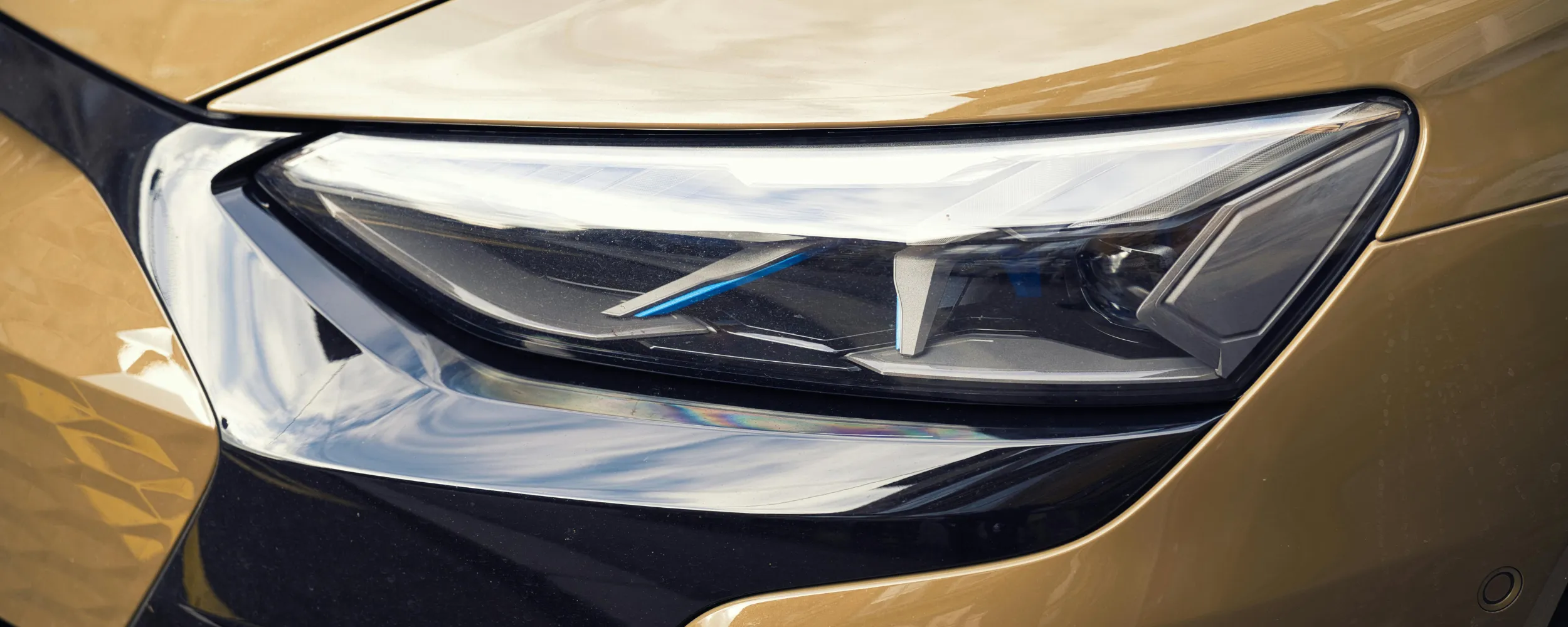 Faro delantero de coche dorado con cristal transparente y tecnología LED moderna