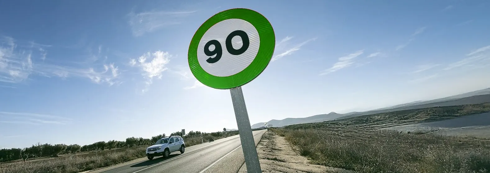 Señal de tráfico verde con límite de velocidad 90 km/h en carretera