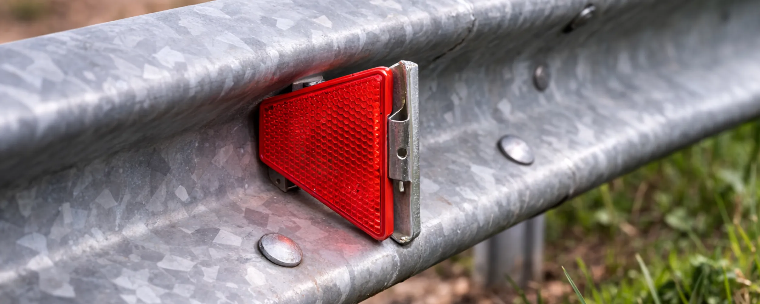 Reflector rojo de balizamiento instalado en guardarraíl metálico de carretera
