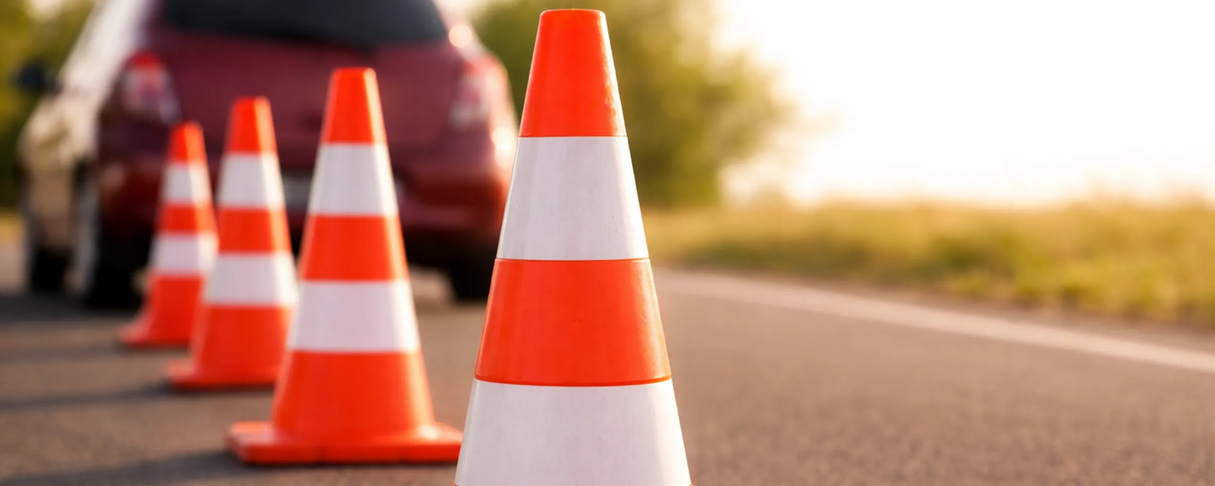 Conos de balizamiento rojo y blanco alineados en una carretera para delimitar zona