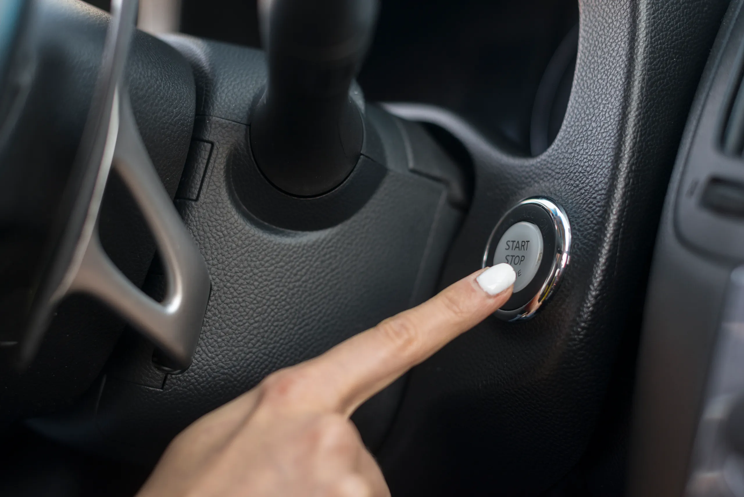 Dedo presionando el botón Start Stop del panel de control de un automóvil