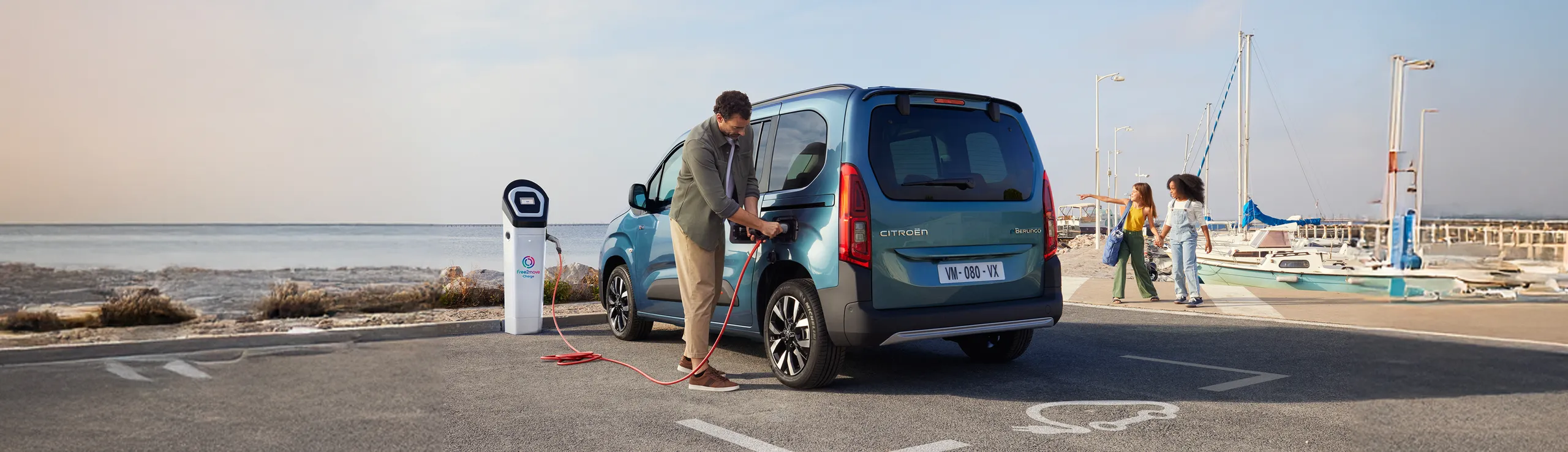Citroën Berlingo azul cargándose en estación de recarga eléctrica junto al mar