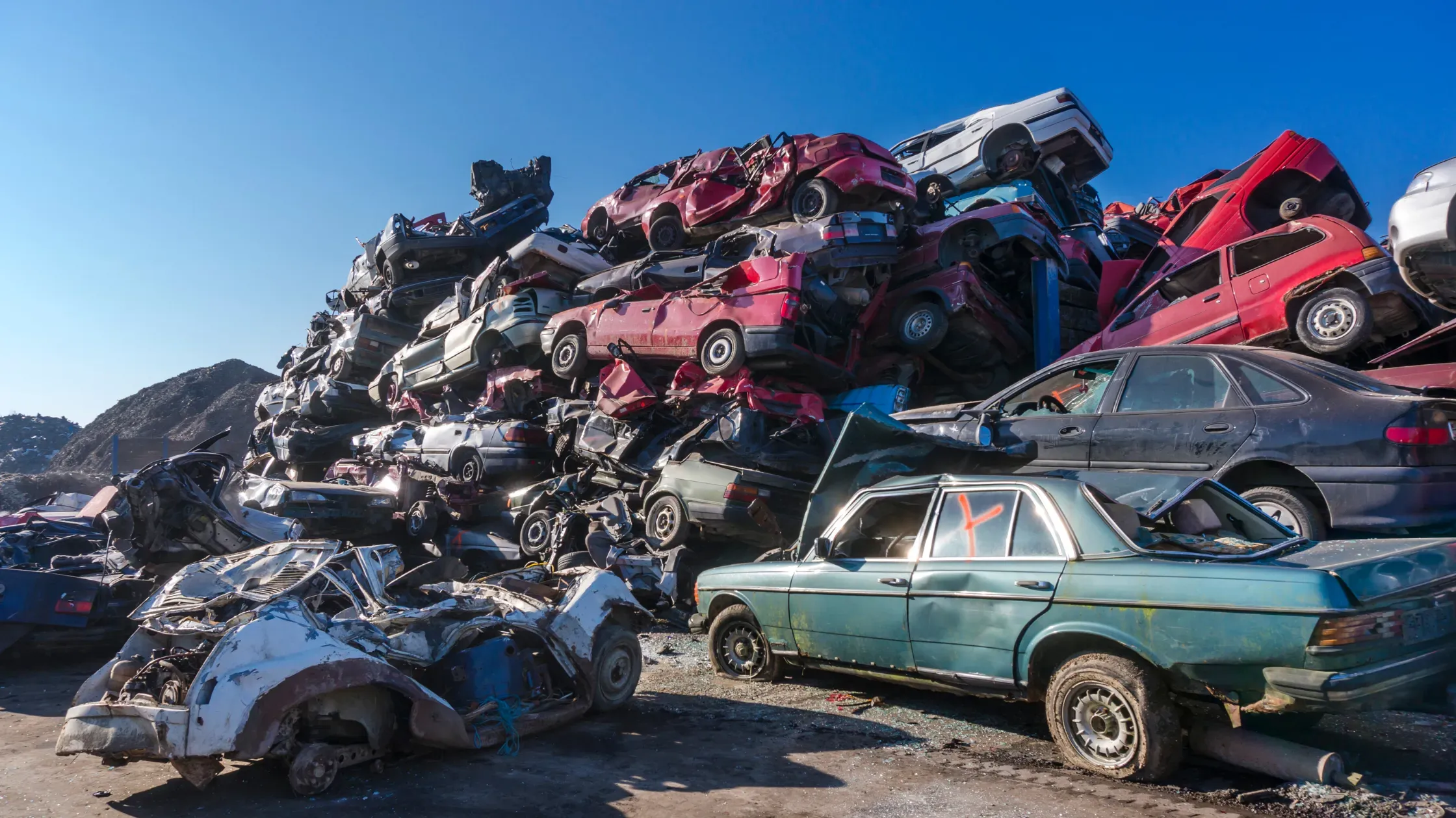 Desguace de vehículos apilados mostrando coches compactados para reciclaje