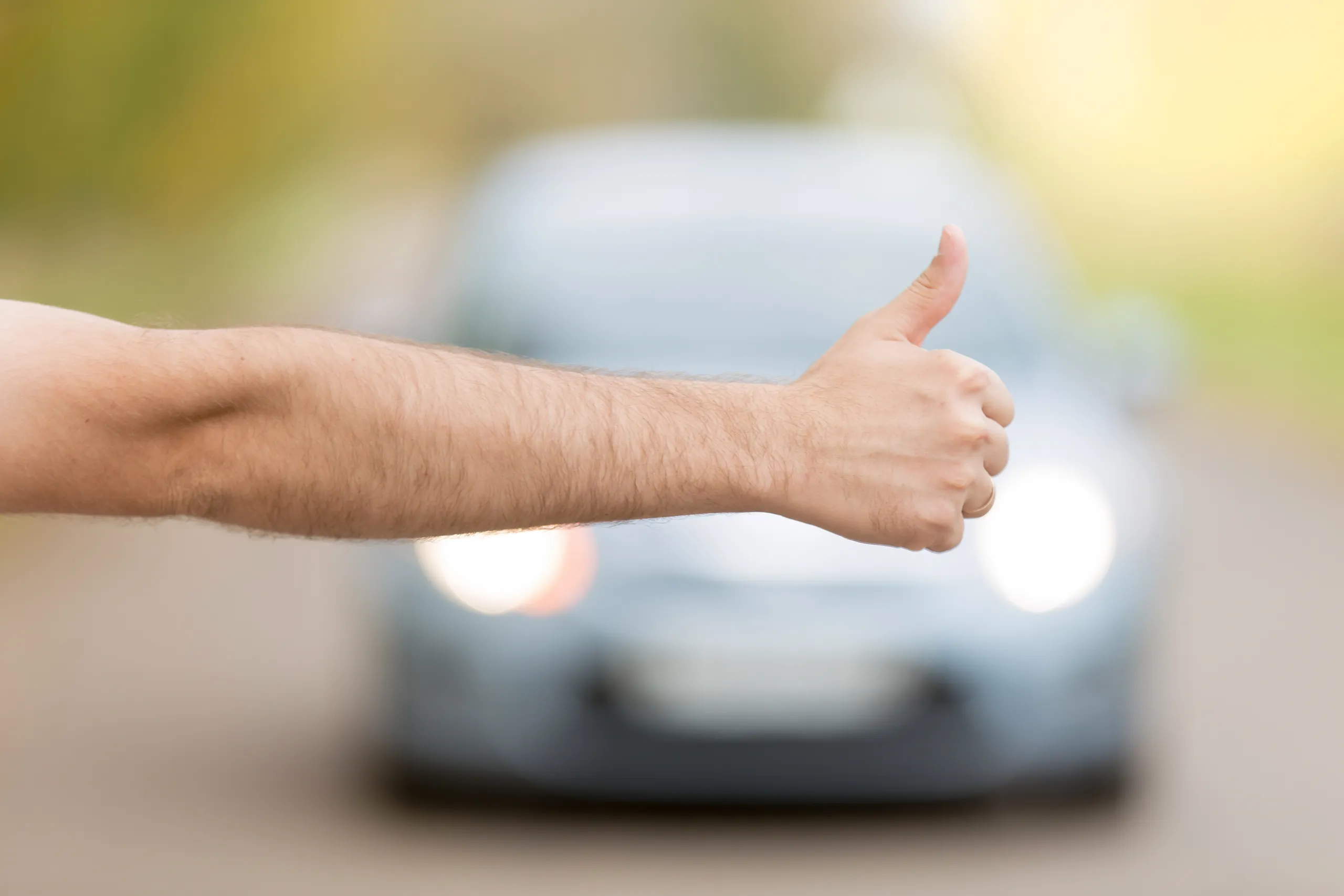 Pulgar hacia arriba de un hombre frente a un coche de ocasión en segundo plano