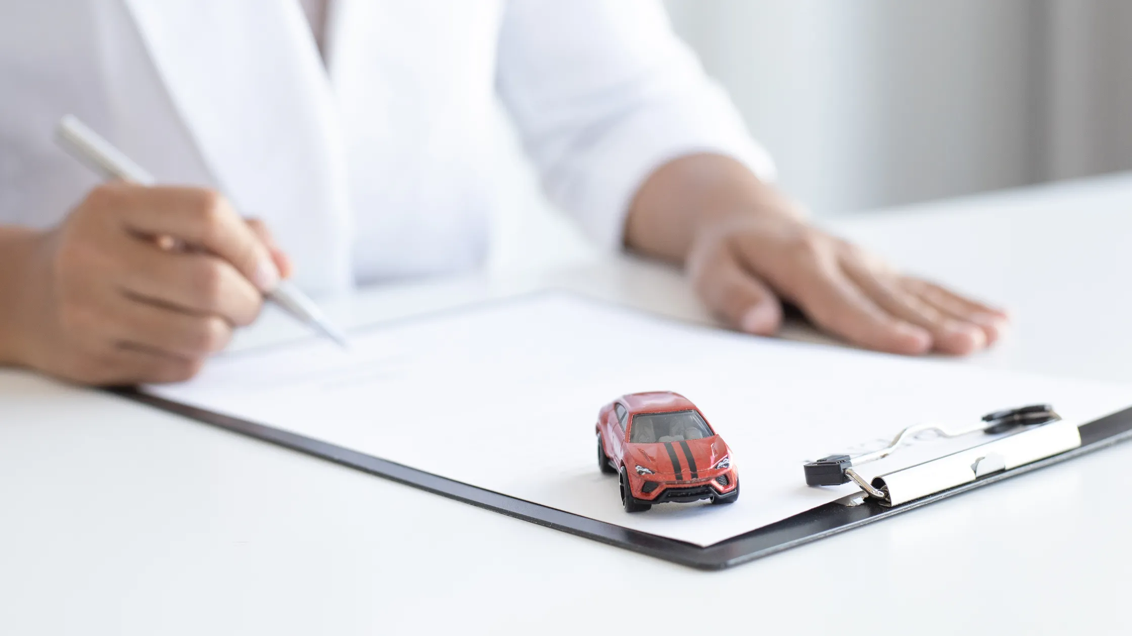 Profesional firma documentos de venta de vehículo con coche en miniatura
